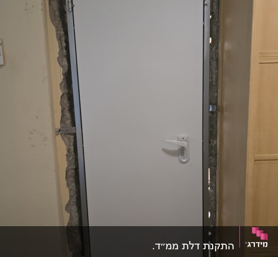 דלת מתכת עם ידית ומנעול מותקנת בקיר